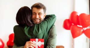 Muž s úsmevom prijíma zážitkový darček vo forme darčekovej poukážky od partnerky.