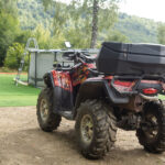 Štvorkolka ťahá príves s nákladom pri práci na poli