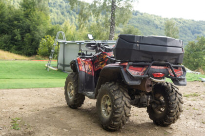 Štvorkolka ťahá príves s nákladom pri práci na poli