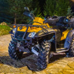 Štvorkolka preváža náklad po dvore a následne jazdí po poli, ukazuje jej praktické využitie pri rôznych pracovných činnostiach.