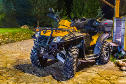 Štvorkolka preváža náklad po dvore a následne jazdí po poli, ukazuje jej praktické využitie pri rôznych pracovných činnostiach.